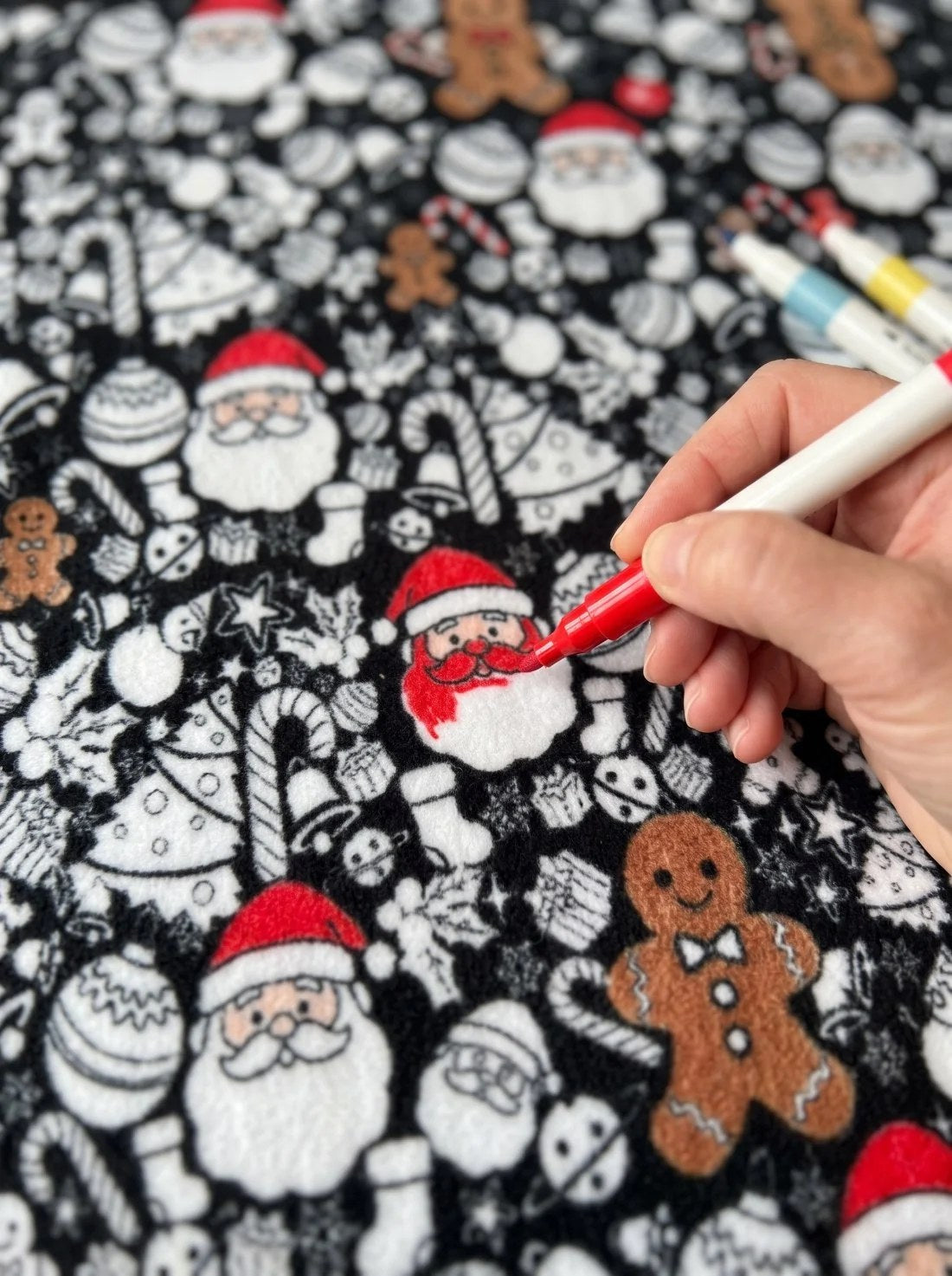 A hand colouring a Santa red on the fleece with a fabric marker