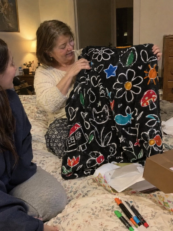 An older woman holding up the folded blanket beside torn wrapping paper