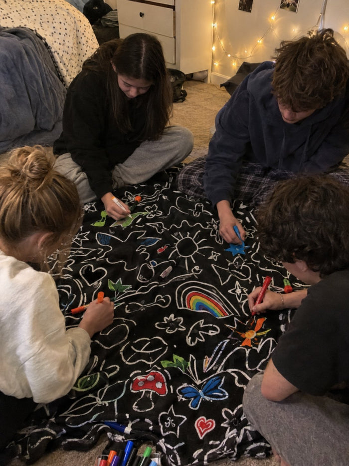Four teenagers sitting round the blanket on a bedroom floor