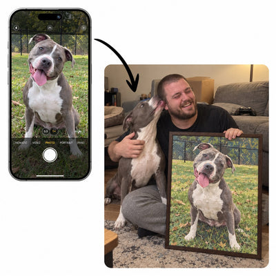 Phone photo of a pit bull next to its owner holding the framed custom paint by numbers painting of the dog
